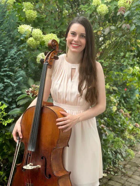 Julia Sterki mit ihrem Cello vor Blumen in einem Garten