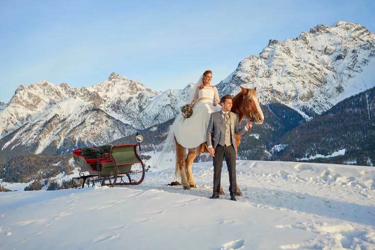 Hochzeitspaar auf Pferdekutsche in Winterlandschaft.