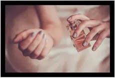 Frau sprüht Parfüm auf ihr Handgelenk