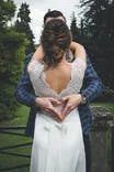 Hochzeitspaar hält sich in den Armen und Bräutigam hält seine Finger zu einem Herz