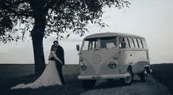 Brautpaar hält sich in den Armen neben eines VW Bus