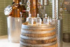 Drei Ginflaschen auf einem Fass in der Gin Distillerie von Edelwhite Gin