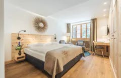 Gemütliches Zimmer mit Holzboden und Bett im Parkhotel Margna