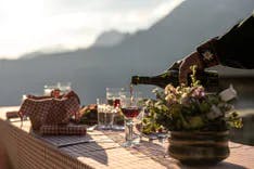 Gedeckter Tisch mit Weingläser und Blumendekoration mit Bergen im Hintergrund