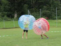 Zwei Bubble Soccer Teilnehmer draussen auf dem Rasen 