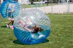 Weibliche Teilnehmerin liegt in einem Bubble Soccer auf dem Rücken
