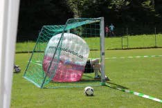 Bubble Soccer mit Fussballtor im Hintergrund