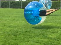 Bubble Soccer Spieler fliegt auf den Ball nach einem Bodycheck 