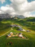 Blick auf das Berghotel Hahnenmoos mit grüner Natur sowie Bergen im Hintergrund