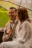 Brautpaar sitzt mit Regenschirm nebeneinander
