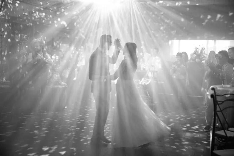 Brautpaar beim Tanzen mit Gästen im Hintergrund