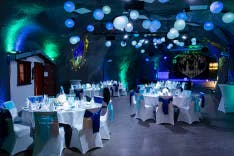 Beleuchteter Saal mit gründ und blau sowie weiss gedeckte Tische für ein Hochzeitsessen