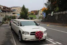 Parkierte weisse Limousine für eine Hochzeit mit Blumendekoration auf der Motorenhaube