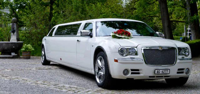 Weisse Limousine mit Blumenschmuck bereit für eine Hochzeitsfeier