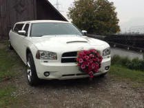 Weisse Limousine mit Blumenschmuck vor einem Holzschuppen für eine Hochzeit