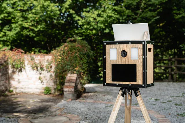 Aufgestellte Fotobox aus Holz mit Wald im Hintergrund