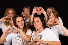 Gruppe von Frauen machen ein Herz aus den eigenen Fingern bei einem Fotoshooting eines Junggesellenabschieds