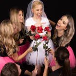 Freundinnen geben der Braut jeweils eine Rose beim Fotoshooting