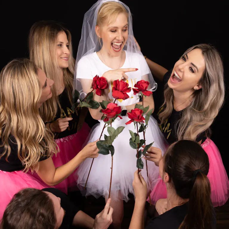Freundinnen geben der Braut jeweils eine Rose beim Fotoshooting